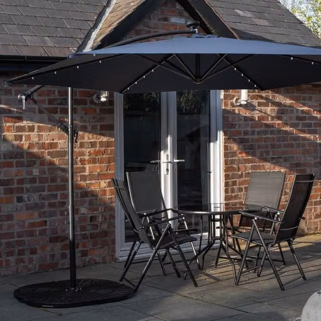 Samuel Alexander 4 Person Round Glass Top Garden Dining Set with Blue Banana Lit Parasol and Base in Black